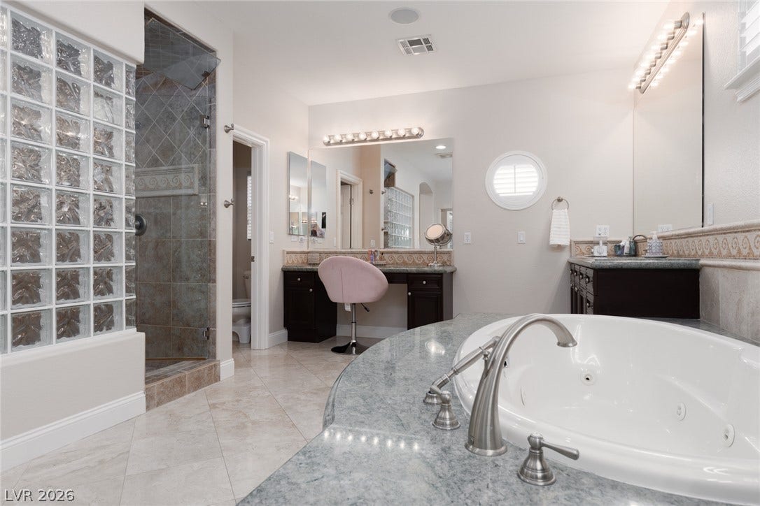 9795 Amador Ranch Avenue, Las Vegas, NV 89149 Fine stone tile flooring sweeps across a well-appointed bathroom featuring a deep soaking tub.