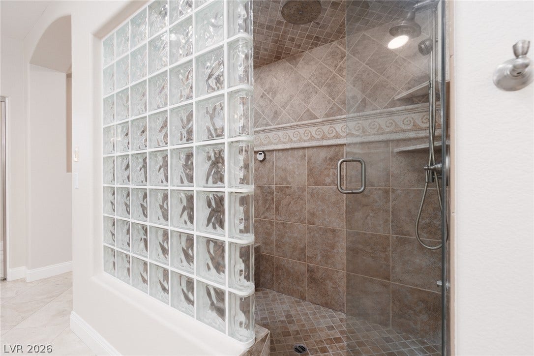 9795 Amador Ranch Avenue, Las Vegas, NV 89149 A walk-in shower showcases custom tile surrounds and a decorative glass block wall.