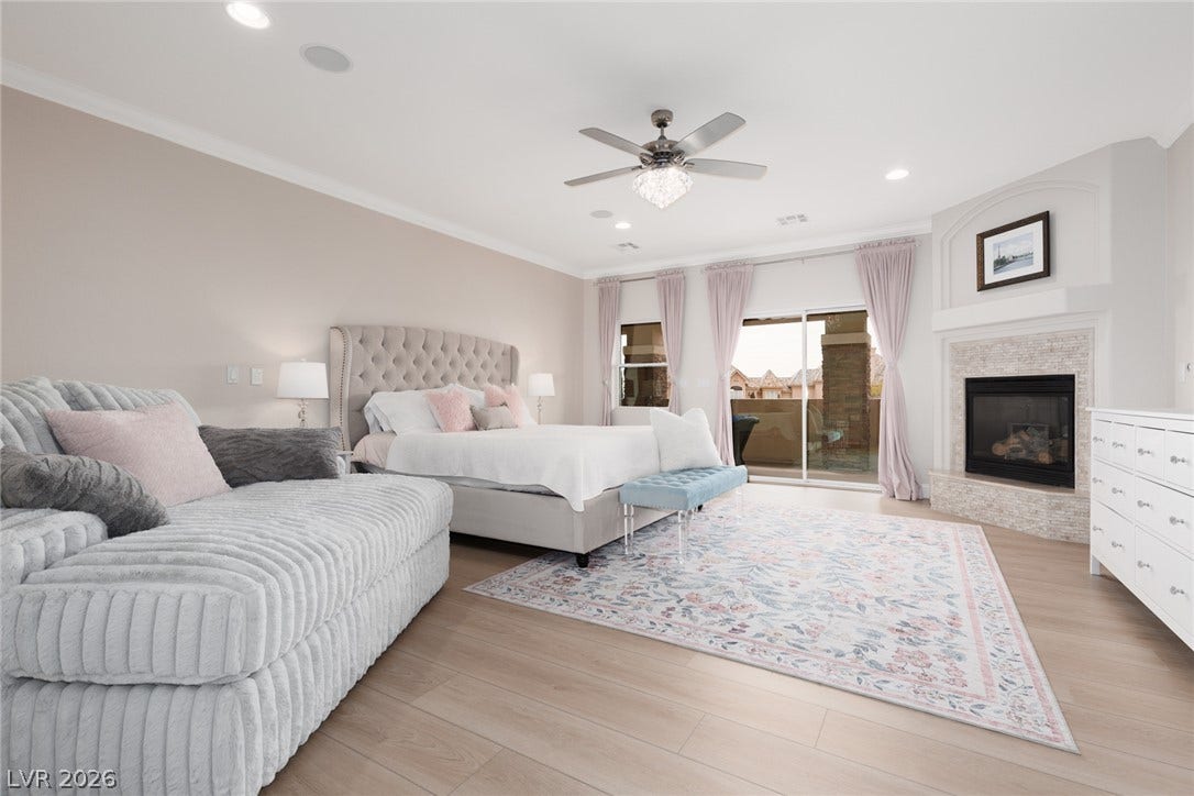 9795 Amador Ranch Avenue, Las Vegas, NV 89149 Warm wood flooring and a cozy fireplace define this comfortable main suite retreat.
