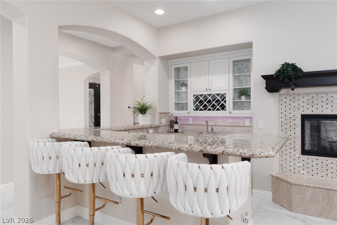 9795 Amador Ranch Avenue, Las Vegas, NV 89149 An elegant wet bar features granite countertops alongside a beautifully tiled fireplace.