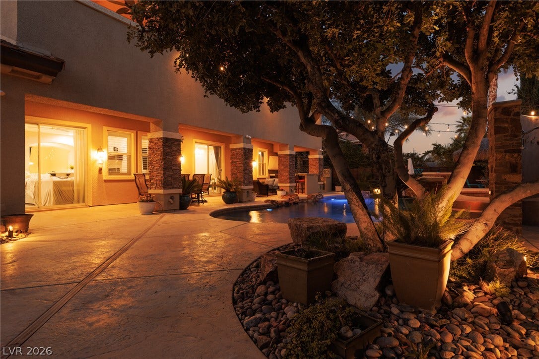 9795 Amador Ranch Avenue, Las Vegas, NV 89149 Inviting stone pillars and a textured concrete patio frame this back yard oasis at dusk.