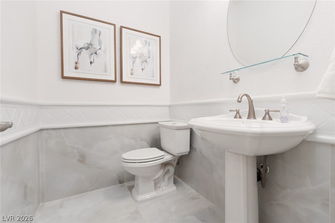 9795 Amador Ranch Avenue, Las Vegas, NV 89149 Elegant wainscoting and stone tile flooring define this classic powder room.