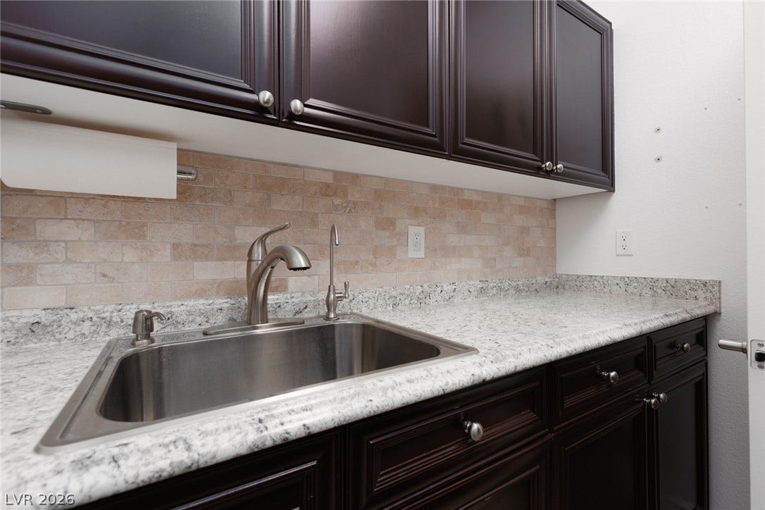 9795 Amador Ranch Avenue, Las Vegas, NV 89149 Rich dark cabinetry pairs beautifully with polished granite countertops and a classic tiled backsplash.