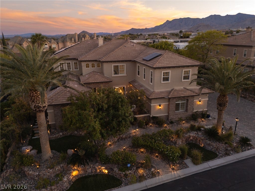 9795 Amador Ranch Avenue, Las Vegas, NV 89149 Dramatic mountain backdrops frame this multi-level desert estate featuring tiled roofing and meticulous stone accents.