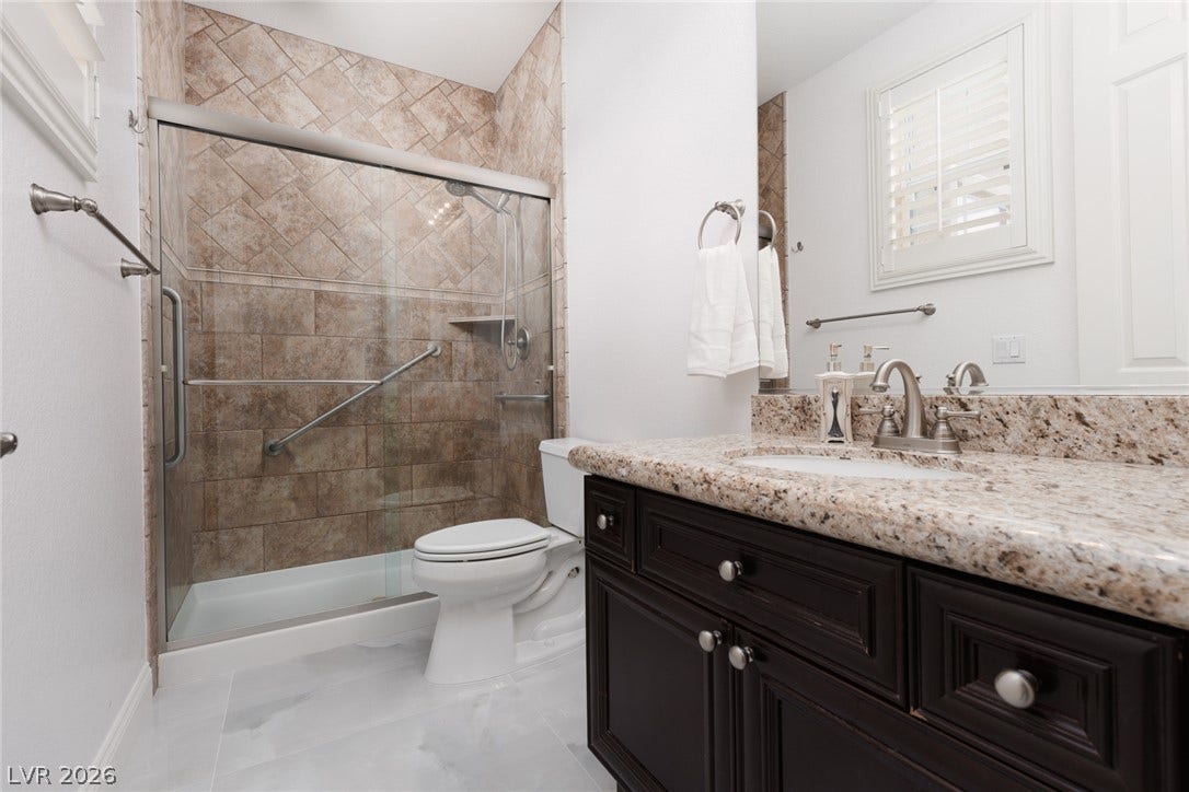 9795 Amador Ranch Avenue, Las Vegas, NV 89149 Polished granite countertops complement a dark vanity and tiled walk-in shower.