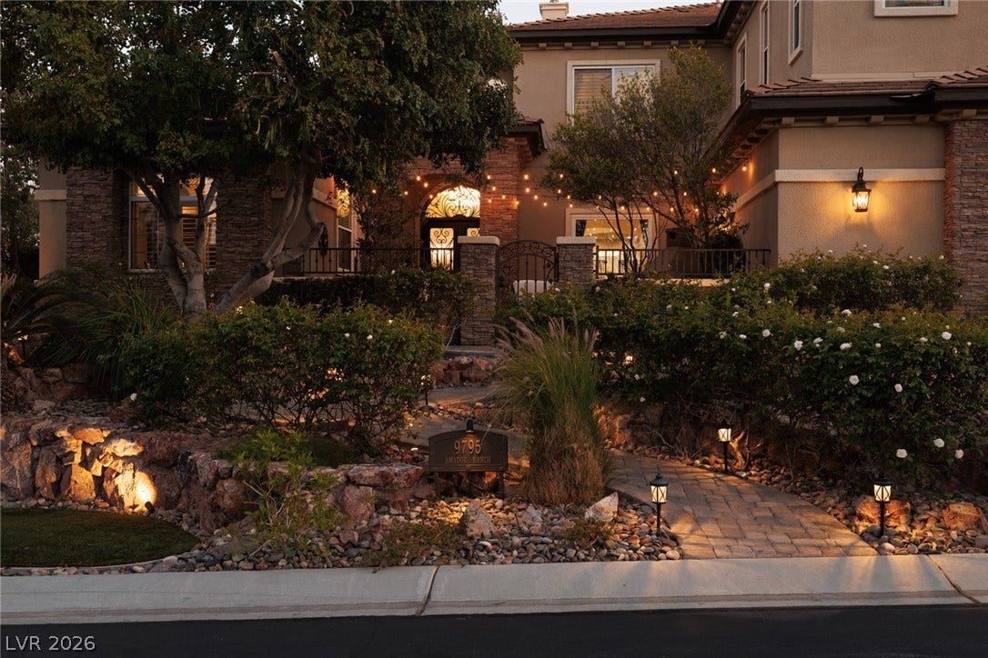9795 Amador Ranch Avenue, Las Vegas, NV 89149 A stone pathway winds past curated landscaping and stone-faced walls to a gated entry courtyard.