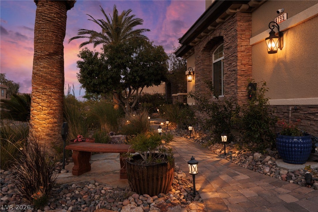 9795 Amador Ranch Avenue, Las Vegas, NV 89149 A stone-paved walkway guides the way past detailed rock landscaping under warm exterior lighting.