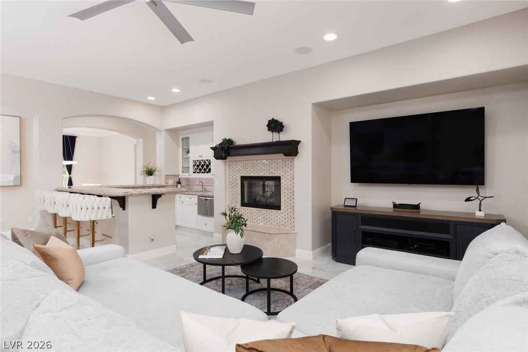 9795 Amador Ranch Avenue, Las Vegas, NV 89149 An open living room displays a tiled fireplace alongside an adjacent kitchen island bar.