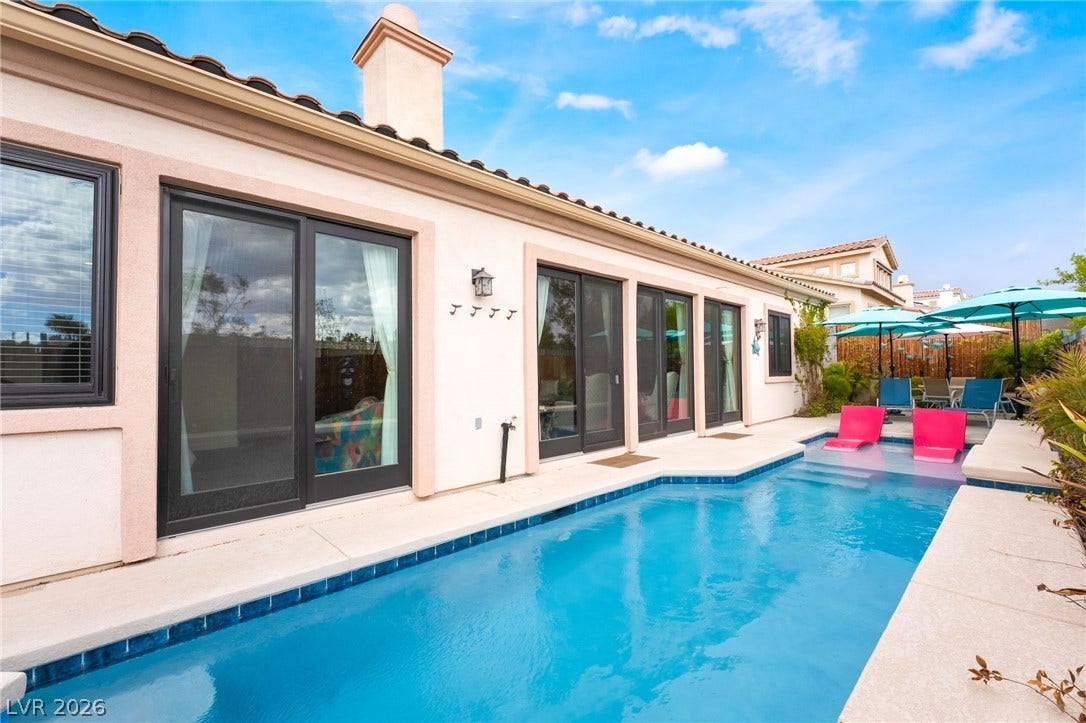 3033 Via Meridiana, Henderson, NV 89052 A sparkling swimming pool runs alongside the stucco exterior of this coastal-style residence.