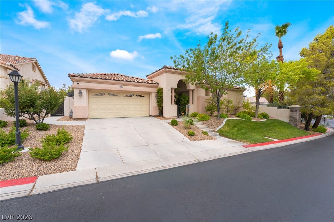 3033 Via Meridiana, Henderson, NV 89052 A spacious driveway leads to this classic Mediterranean-style home under a bright blue sky.
