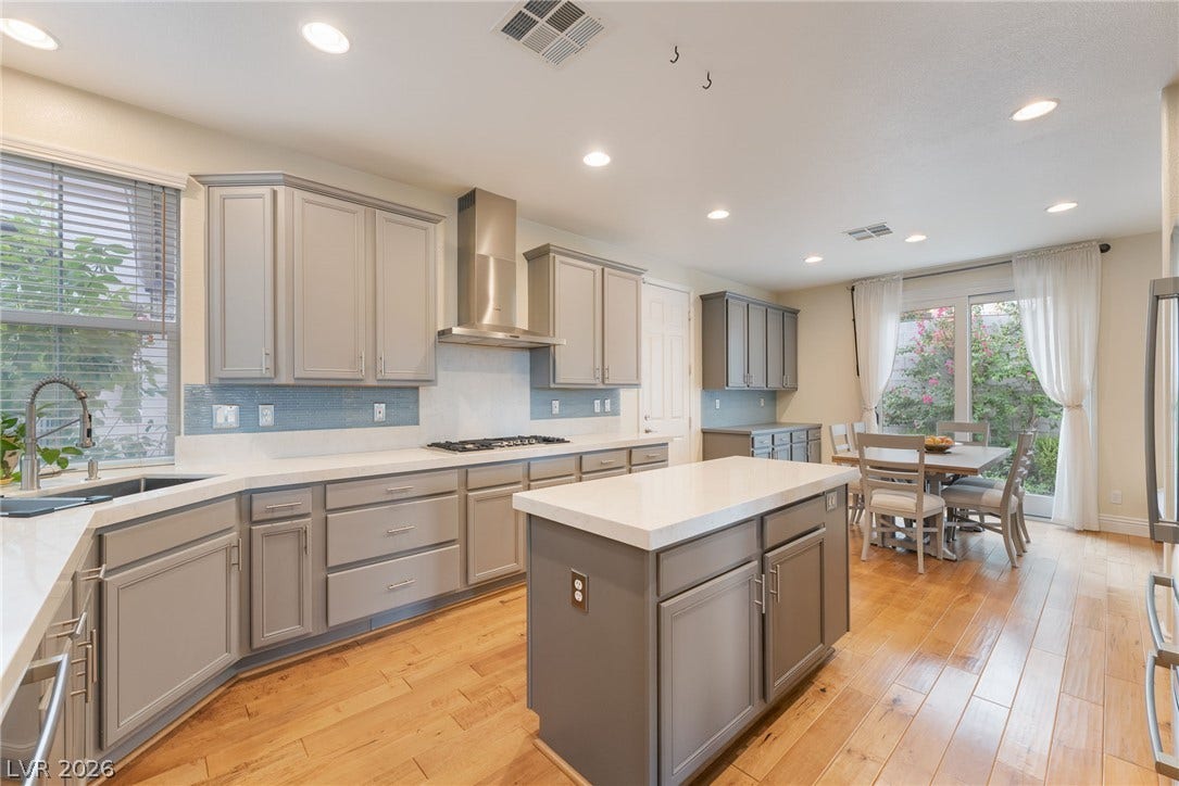 3033 Via Meridiana, Henderson, NV 89052 Polished hardwood floors and a central island anchor this modern kitchen and dining space.