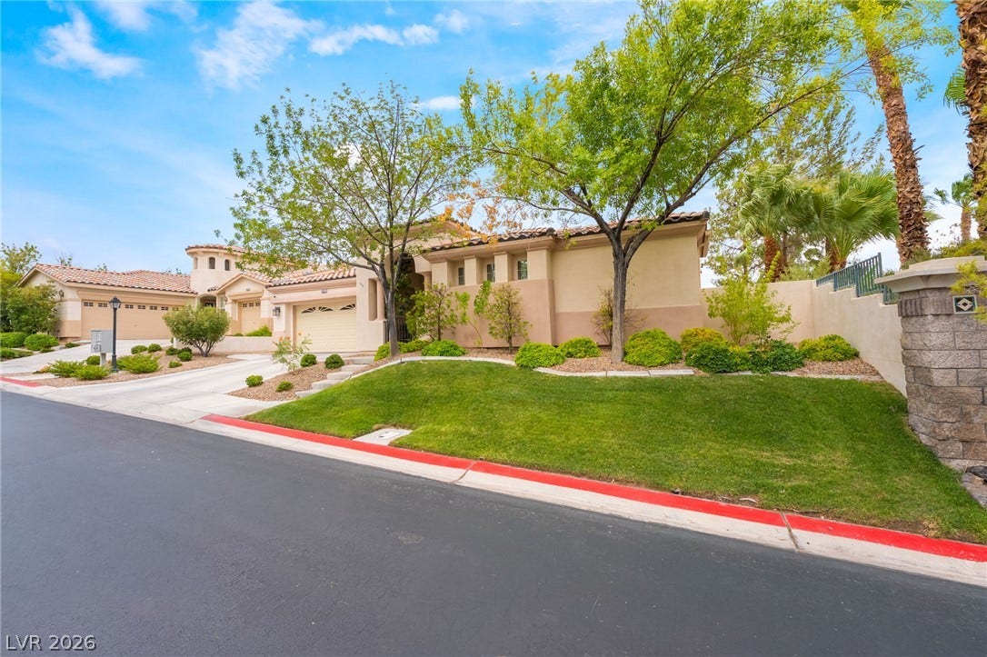 3033 Via Meridiana, Henderson, NV 89052 Manicured green lawns frame this elegant desert home featuring a tiled roof and stucco exterior.