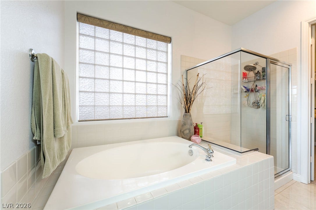 3033 Via Meridiana, Henderson, NV 89052 Natural light floods this bathroom featuring a large soaking tub and a glass-enclosed shower.
