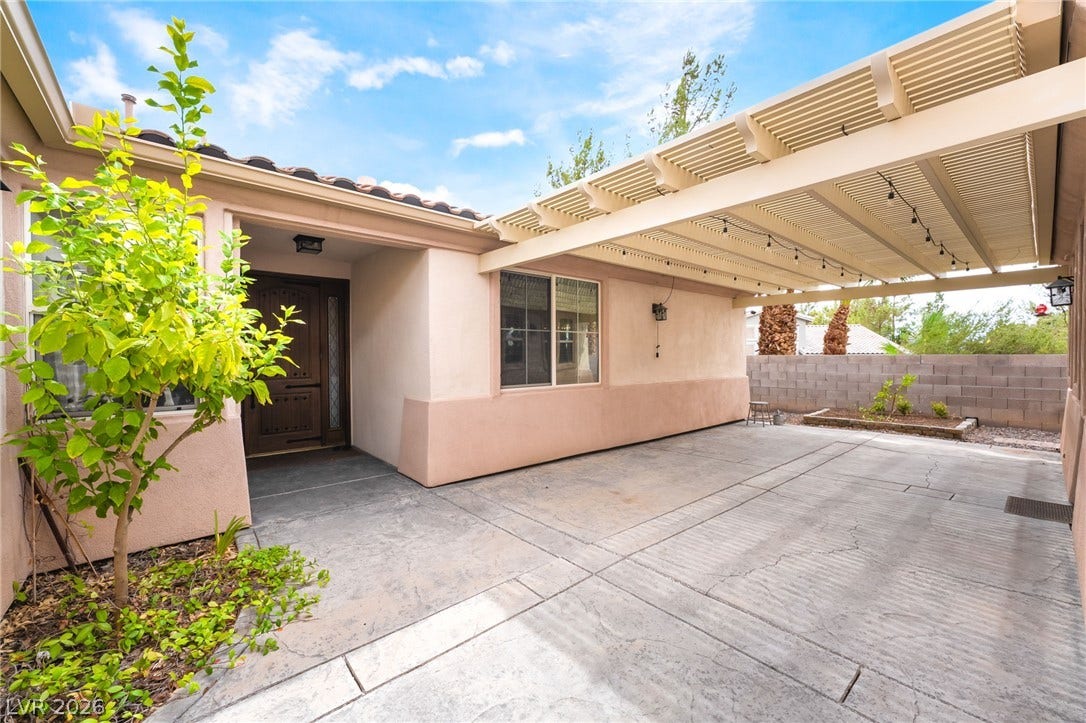 3033 Via Meridiana, Henderson, NV 89052 A spacious stamped concrete patio lies beneath a classic wood pergola structure.