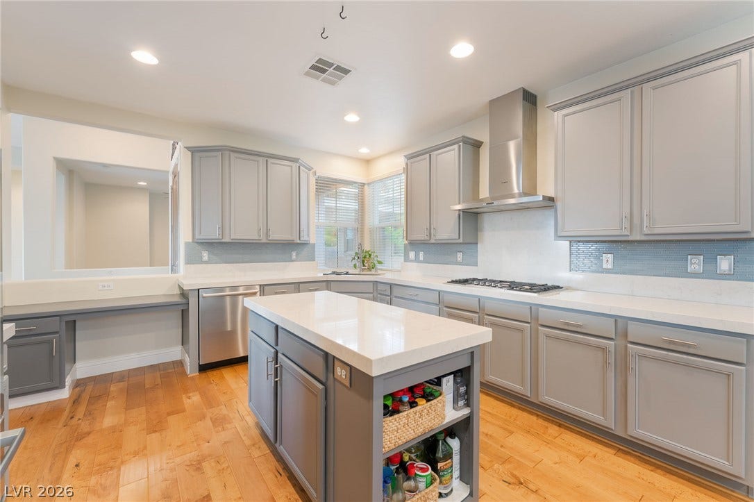 3033 Via Meridiana, Henderson, NV 89052 Smooth stone countertops and classic cabinetry elevate this open kitchen featuring a central island.