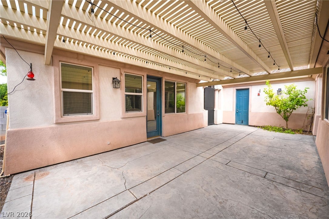 3033 Via Meridiana, Henderson, NV 89052 An expansive concrete patio lies sheltered beneath a structured slatted pergola ceiling.