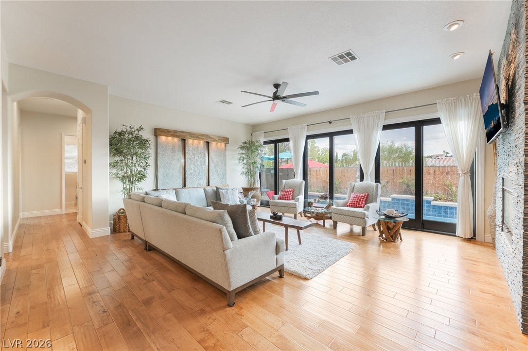 3033 Via Meridiana, Henderson, NV 89052 Rich wood floors and a stone fireplace define this comfortable living space.