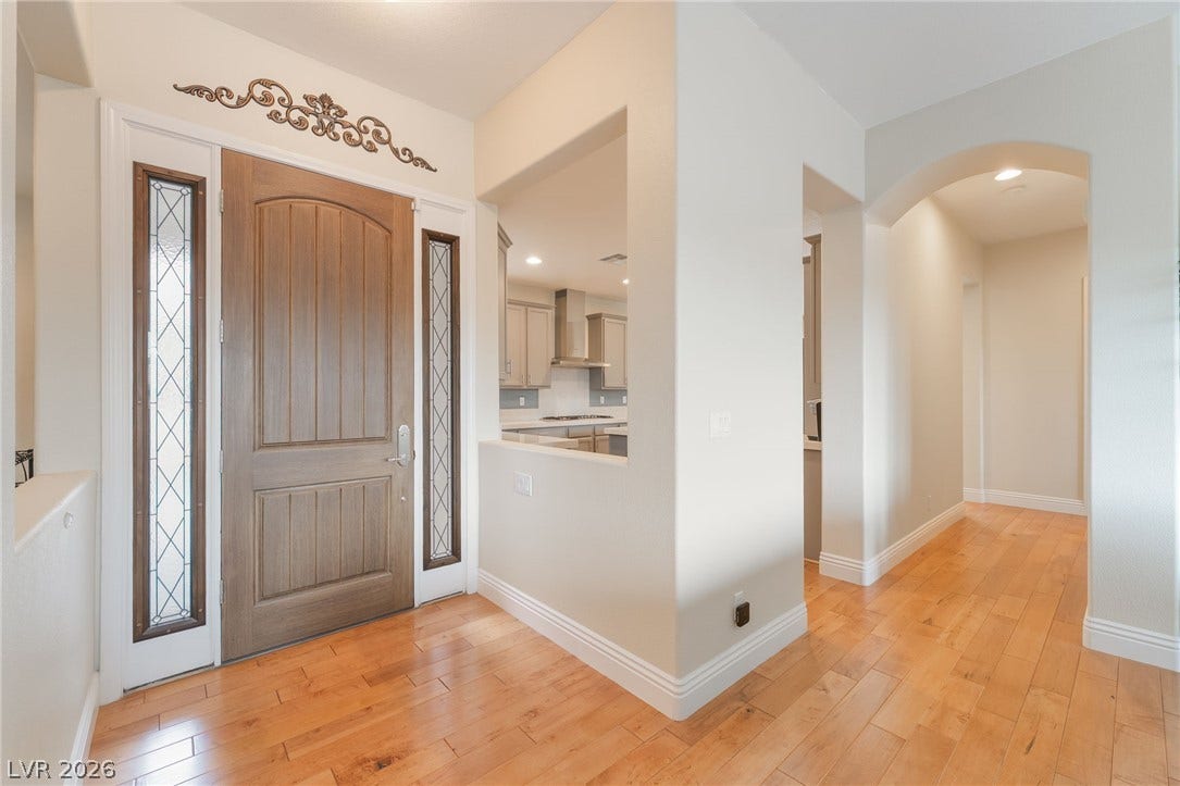 3033 Via Meridiana, Henderson, NV 89052 Rich hardwood floors welcome guests into an inviting entryway featuring elegant architectural cutouts and arched transitions.