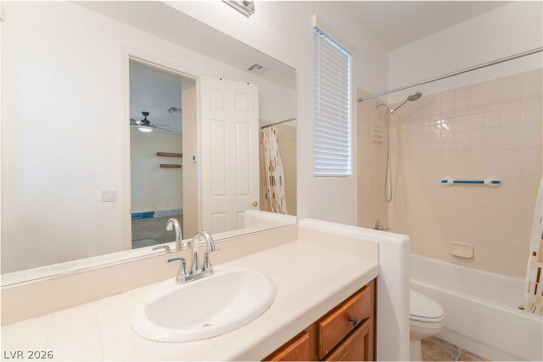 3033 Via Meridiana, Henderson, NV 89052 A classic tiled vanity integrates with a tub shower combination in this functional bathroom layout.
