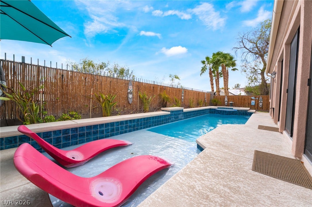 3033 Via Meridiana, Henderson, NV 89052 A sparkling in-ground pool runs alongside concrete decking framed by privacy fencing.