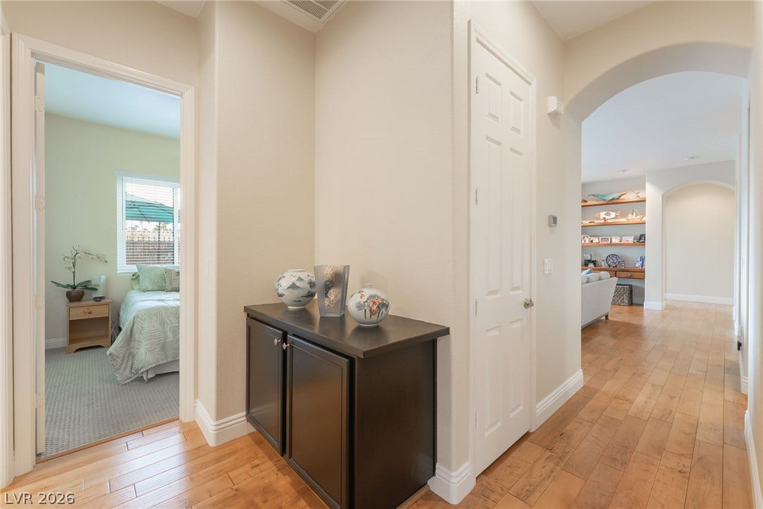 3033 Via Meridiana, Henderson, NV 89052 Gleaming hardwood floors and classic arched doorways define this central hallway transition.