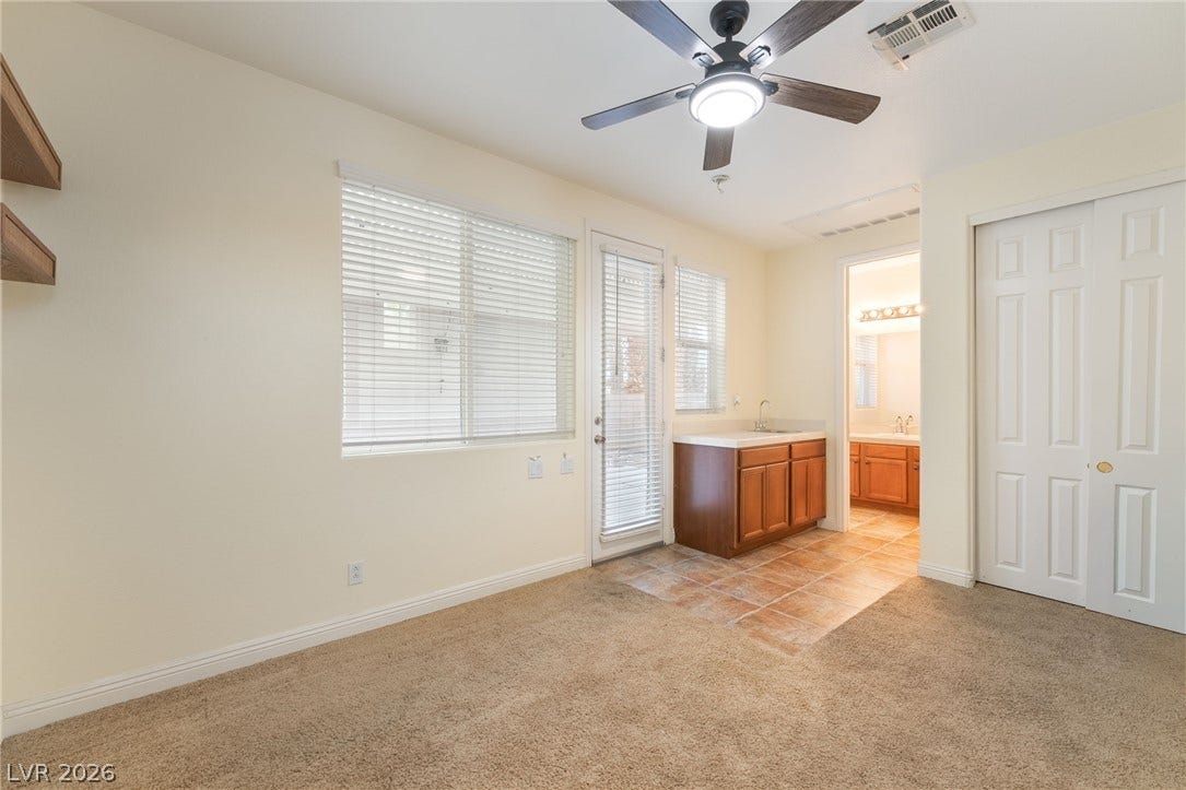 3033 Via Meridiana, Henderson, NV 89052 A spacious room features plush carpeting, a wet bar setup, and direct outdoor access.