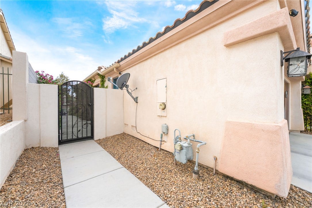 3033 Via Meridiana, Henderson, NV 89052 A neat concrete walkway leads to a secure wrought iron gate along the side yard.