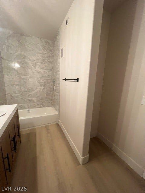 2131 Hussium Hills Street, #208, Las Vegas, NV 89108 A modern bathroom features a tiled tub surround and clean-lined vanity on wood-look flooring.
