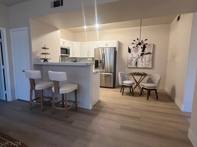 2131 Hussium Hills Street, #208, Las Vegas, NV 89108 An open floorplan seamlessly connects the kitchen and dining areas over handsome wood-style flooring.