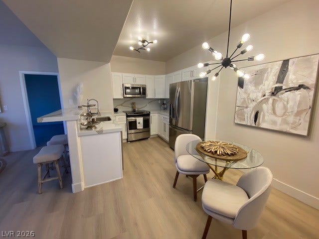 2131 Hussium Hills Street, #208, Las Vegas, NV 89108 An open kitchen and dining area features sleek cabinetry and modern light fixtures.