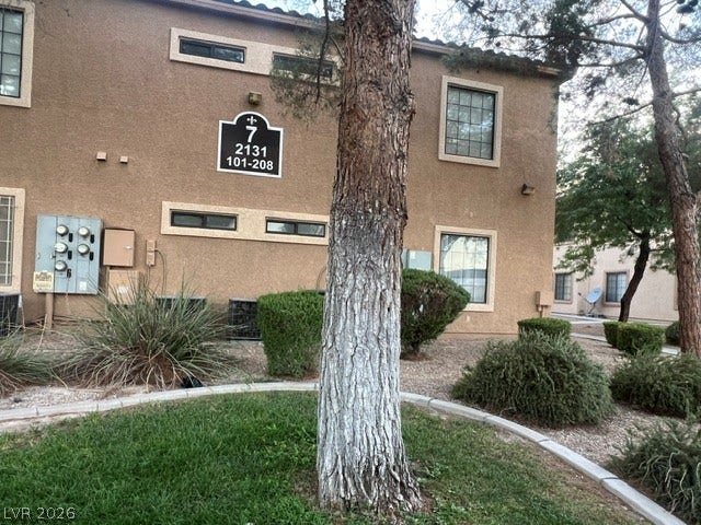 2131 Hussium Hills Street, #208, Las Vegas, NV 89108 Mature trees and neat landscaping frame the classic stucco facade of this multi-family residential building.