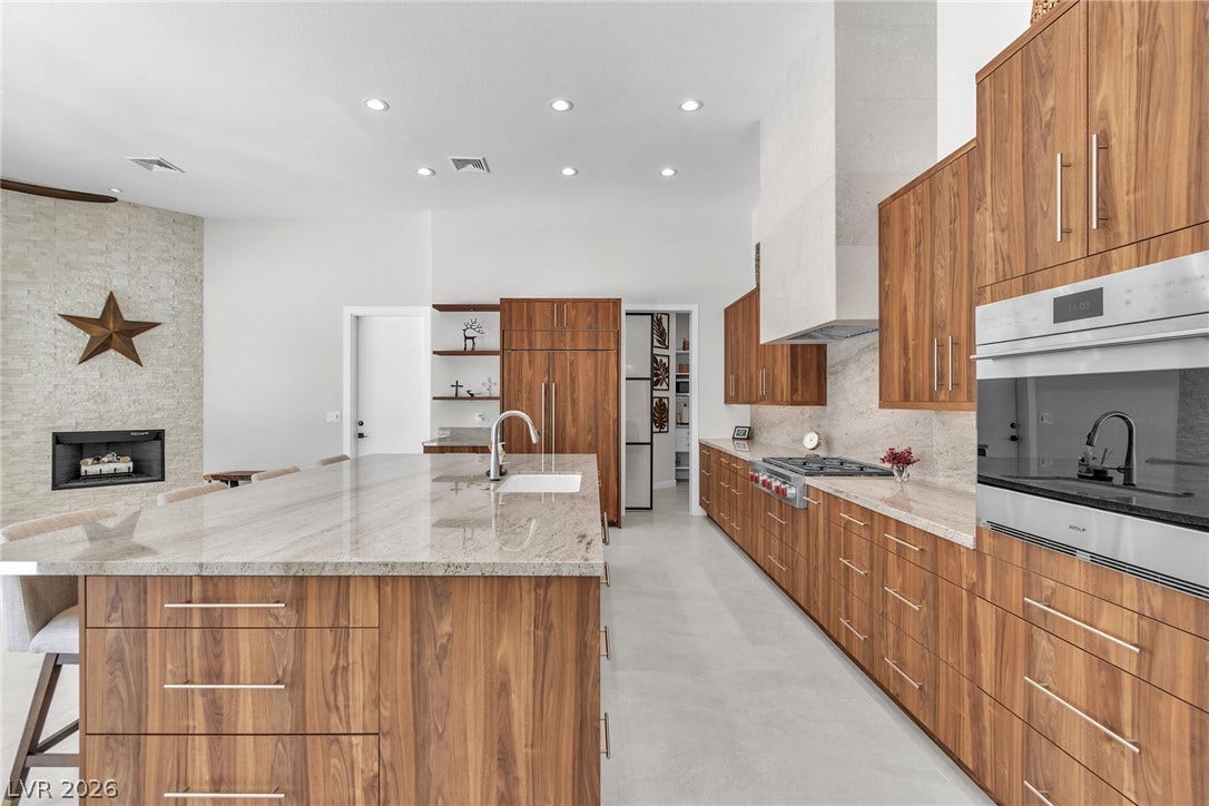1508 Ten Palms Court, Las Vegas, NV 89117 Rich wood cabinetry contrasts beautifully with stone surfaces in this contemporary culinary space.