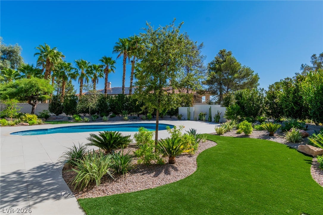 1508 Ten Palms Court, Las Vegas, NV 89117 Lush tropical plantings and manicured turf frame a sparkling swimming pool under clear blue skies.