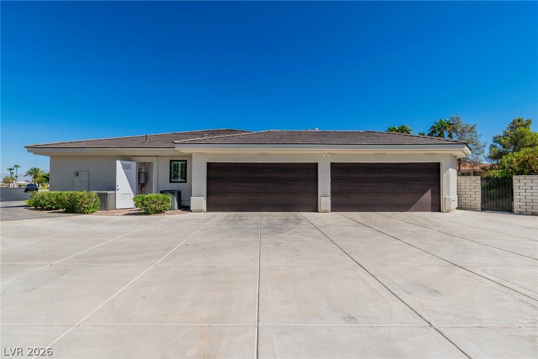 1508 Ten Palms Court, Las Vegas, NV 89117 An expansive concrete driveway leads to a modern three-car garage with dark wood-toned doors.