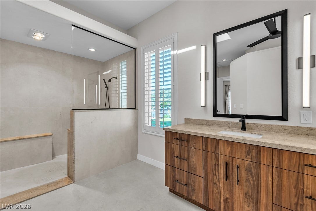 1508 Ten Palms Court, Las Vegas, NV 89117 A stone-topped vanity and concrete-style flooring define this modern bathroom with a walk-in shower.