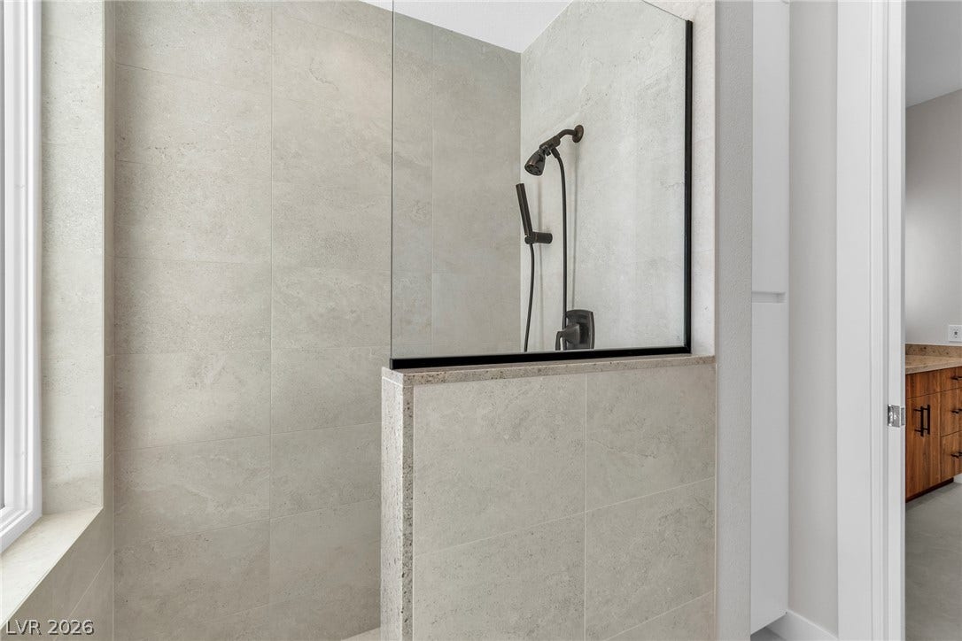 1508 Ten Palms Court, Las Vegas, NV 89117 A modern walk-in shower features large-format stone-look tiling and sleek black fixtures.