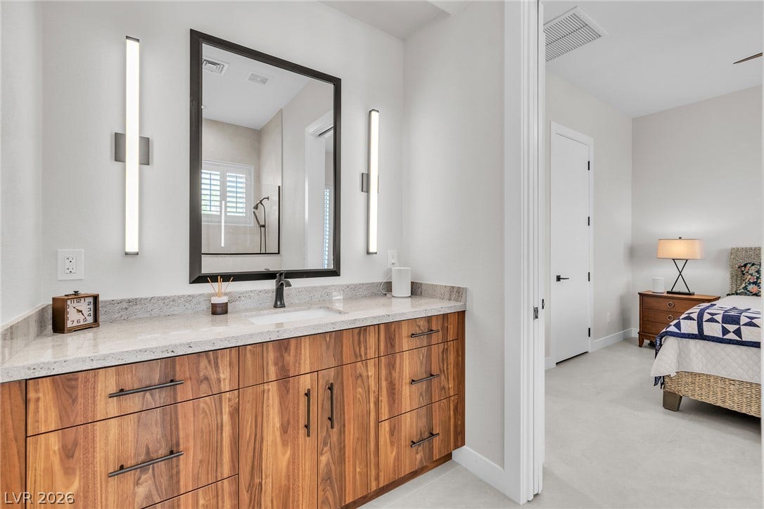1508 Ten Palms Court, Las Vegas, NV 89117 Rich wood cabinetry and stone countertops elevate this contemporary ensuite bath with an adjacent bedroom.