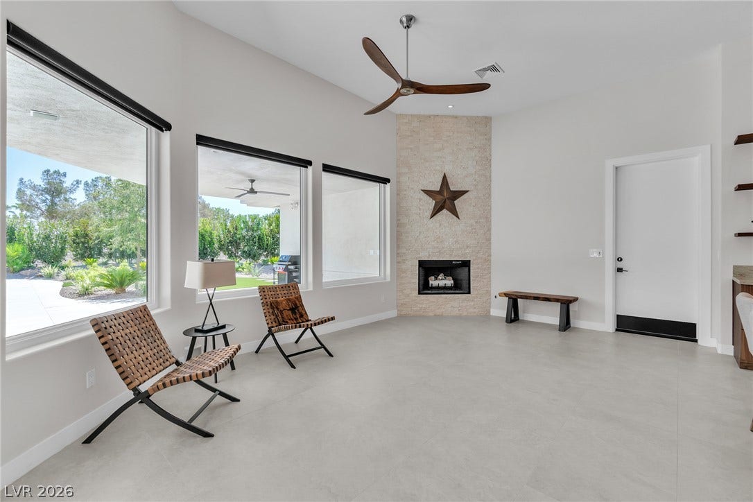 1508 Ten Palms Court, Las Vegas, NV 89117 An inviting stone-faced fireplace anchors the airy living space illuminated by large windows.