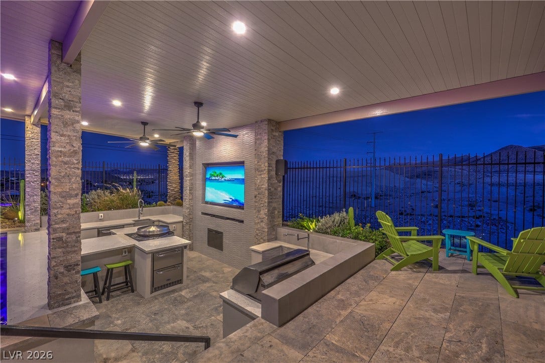 11288 Rebel Dome Court, Las Vegas, NV 89141 An outdoor kitchen sits under a covered patio with stone columns and tile flooring.