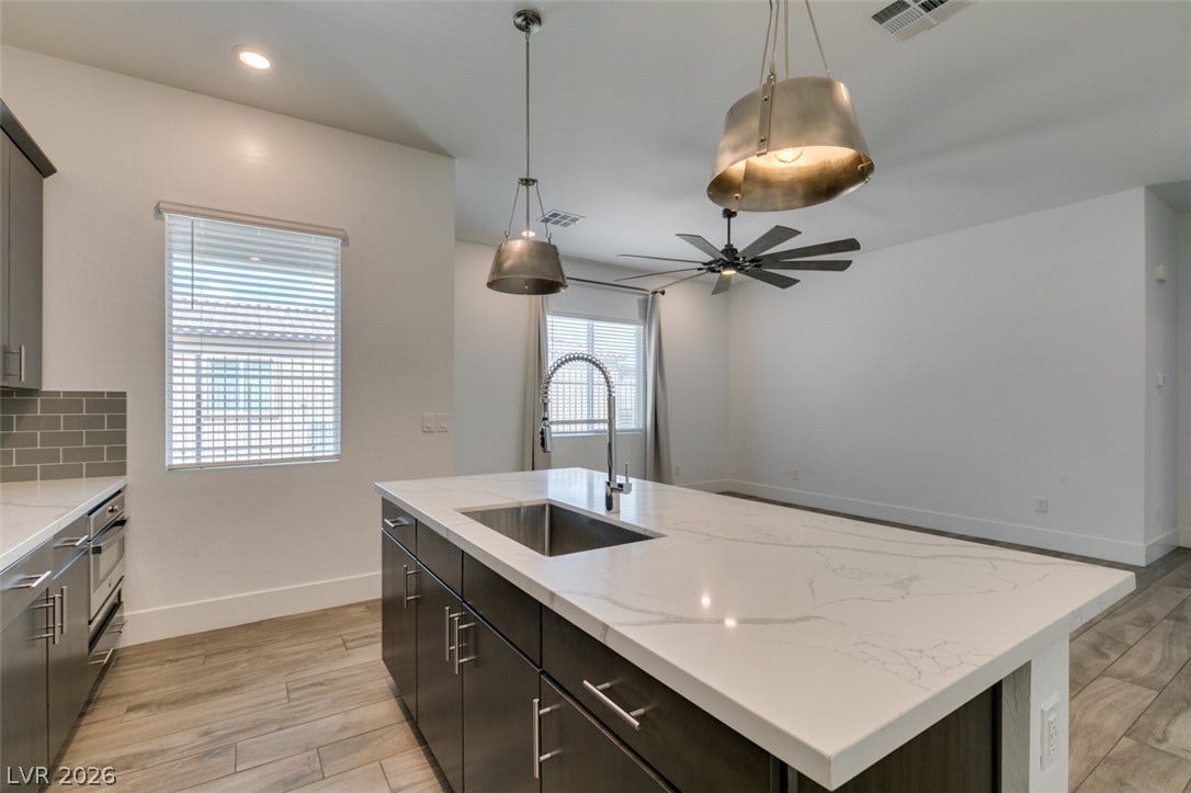 11288 Rebel Dome Court, Las Vegas, NV 89141 Gleaming stone countertops and wood-look tile flooring anchor this airy open kitchen space.