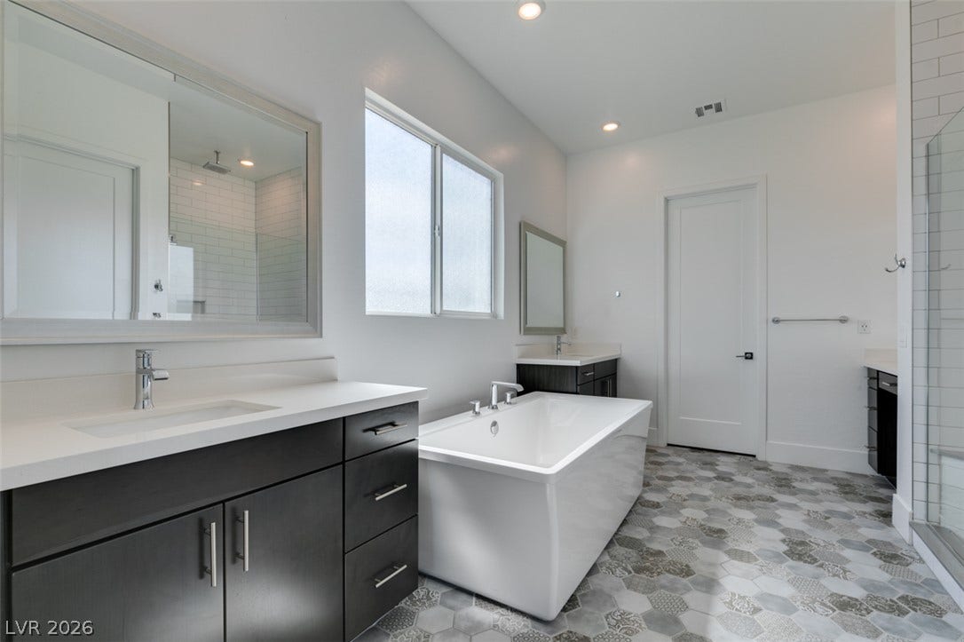 11288 Rebel Dome Court, Las Vegas, NV 89141 Geometric floor tiles and a freestanding tub create a stylish, modern bathroom retreat.