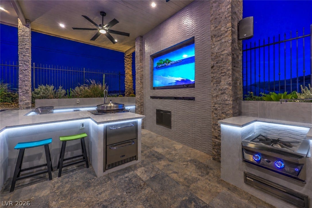 11288 Rebel Dome Court, Las Vegas, NV 89141 Stone pillars and tile flooring define this covered outdoor kitchen space under the evening sky.