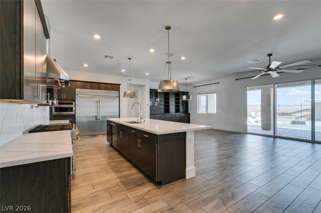 11288 Rebel Dome Court, Las Vegas, NV 89141 Gleaming wood-look tile floors stretch across this modern open kitchen and living space.
