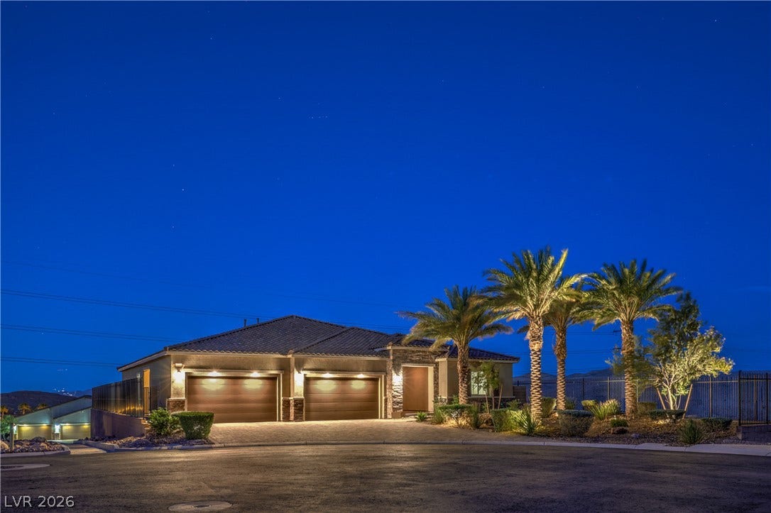 11288 Rebel Dome Court, Las Vegas, NV 89141 Illuminated palm trees frame the stone-accented facade and spacious multi-car garage at twilight.