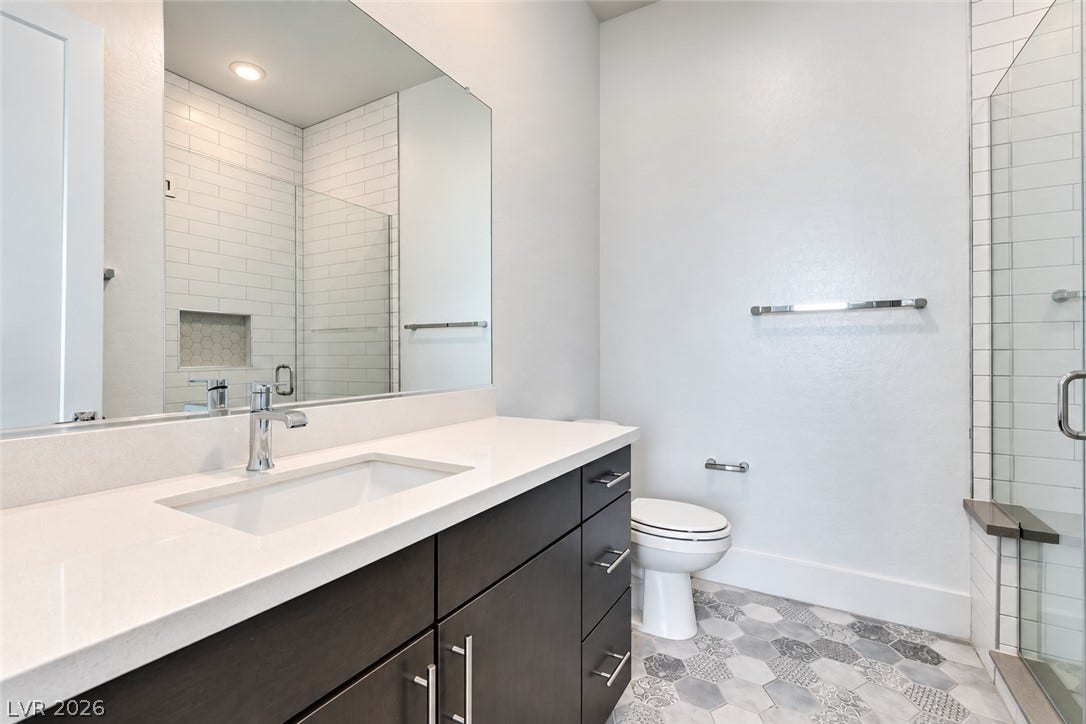 11288 Rebel Dome Court, Las Vegas, NV 89141 Geometric floor tile and stone counters elevate this contemporary bathroom design.