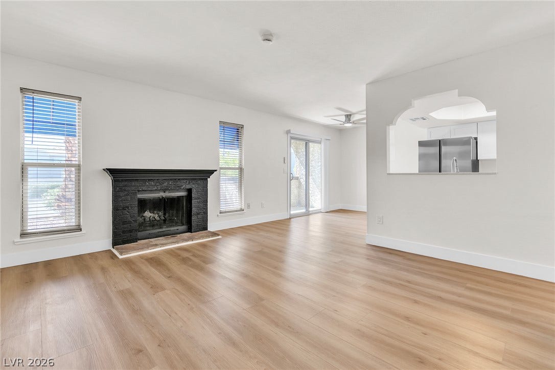 Warm wood-look flooring and a brick fireplace anchor this welcoming open living space.