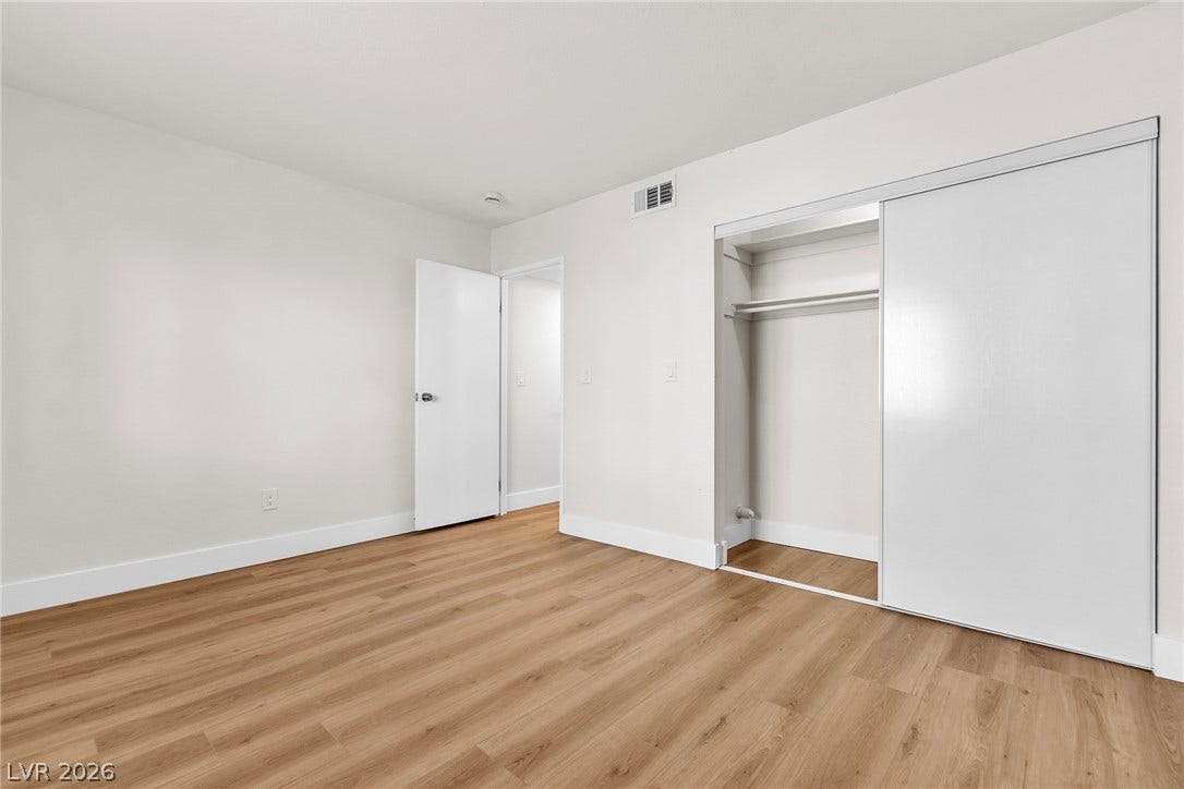 Smooth wood floors and crisp white trim enhance this minimalist, airy bedroom.