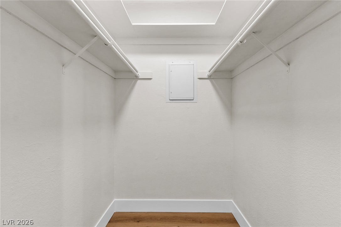 A spacious walk-in closet features built-in wire shelving and durable wood flooring.