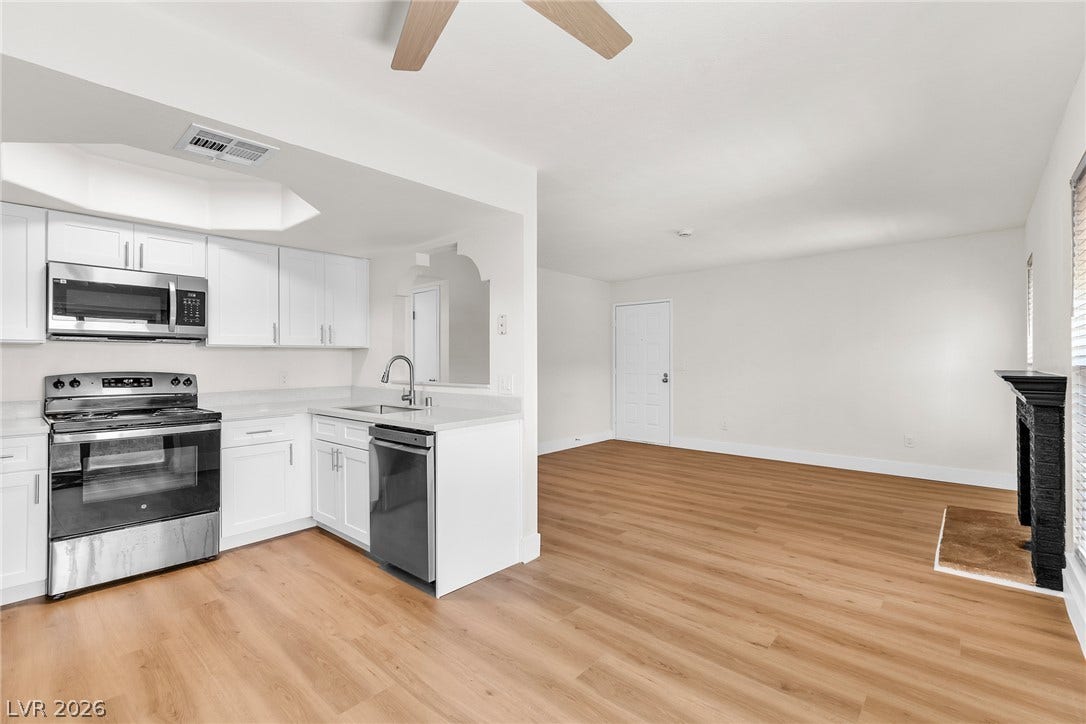 Smooth wood-style flooring anchors the seamless layout connecting kitchen and living spaces.