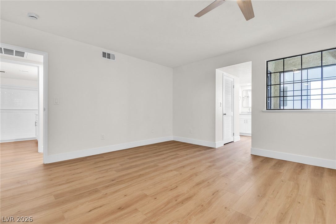 Warm wood flooring and clean white walls anchor this versatile open room.